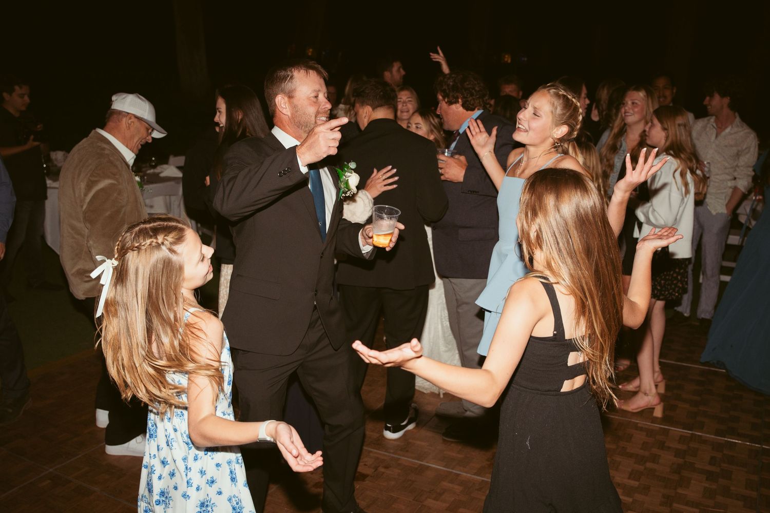 Wedding guests dancing and celebrating together under romantic evening lighting.