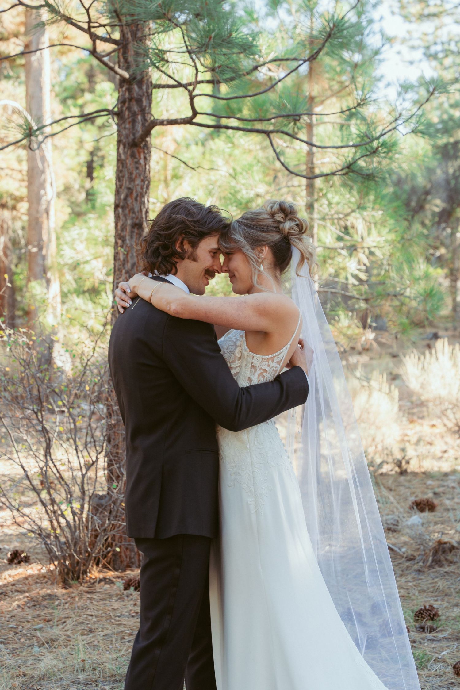 A tender embrace between newlyweds photographed in a serene forest setting.