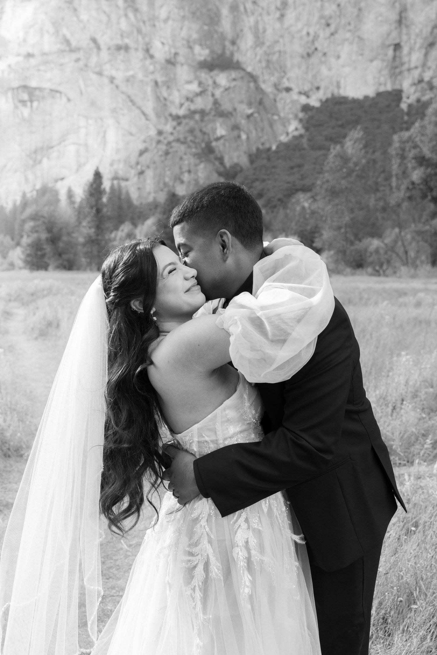 Black and white wedding portrait with dramatic Yosemite cliffs in background.