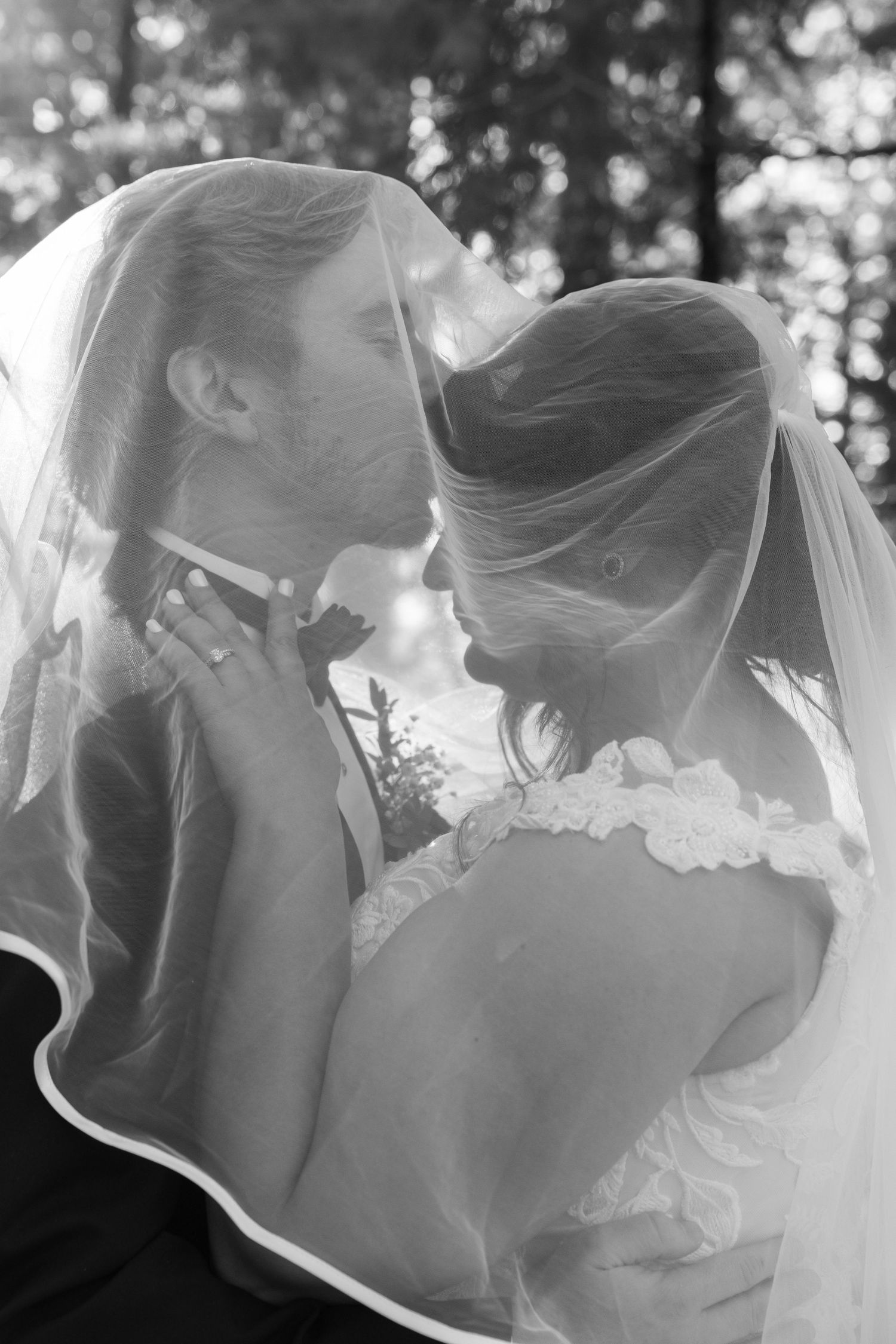 Black and white portrait of an intimate wedding moment under a delicate veil.