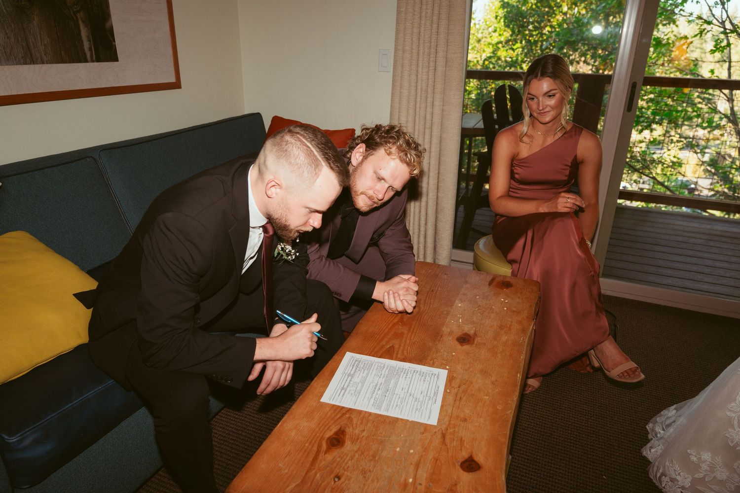 Wedding documents being signed at wooden table during indoor ceremony.