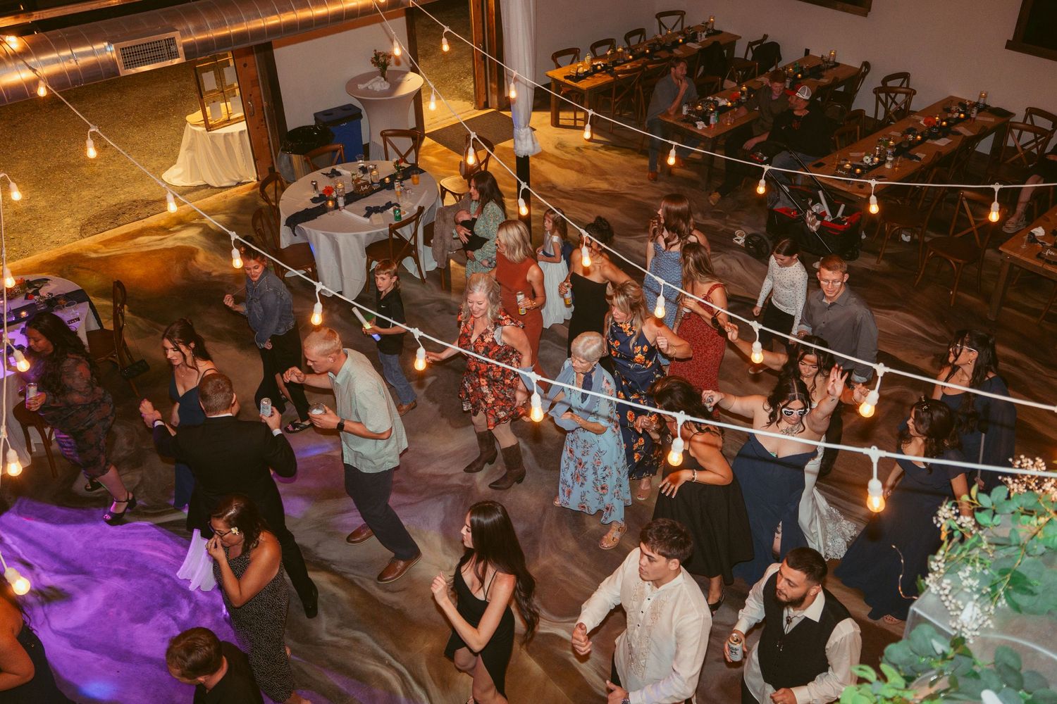 Aerial view of dancers filling a venue space decorated with string lights and ambient lighting.