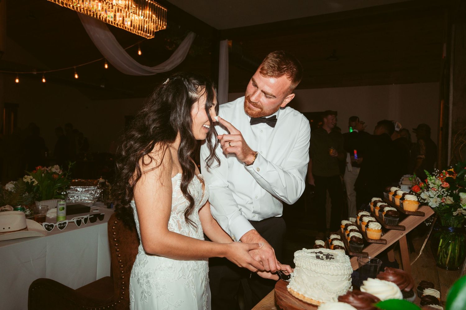 Newlyweds feed each other pieces of white wedding cake during their reception celebration.
