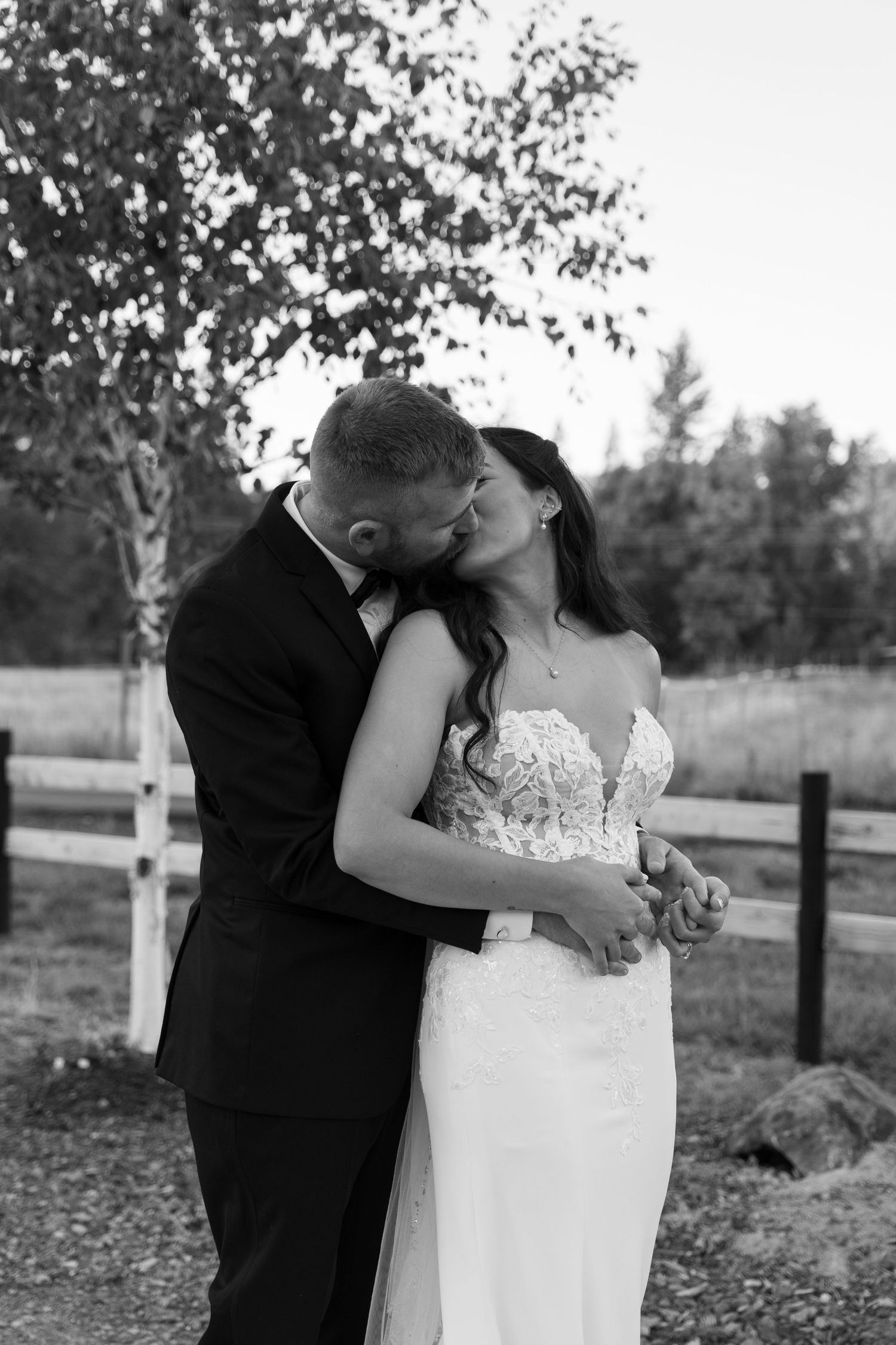 Black and white portrait of wedding couple sharing tender moment in outdoor setting.