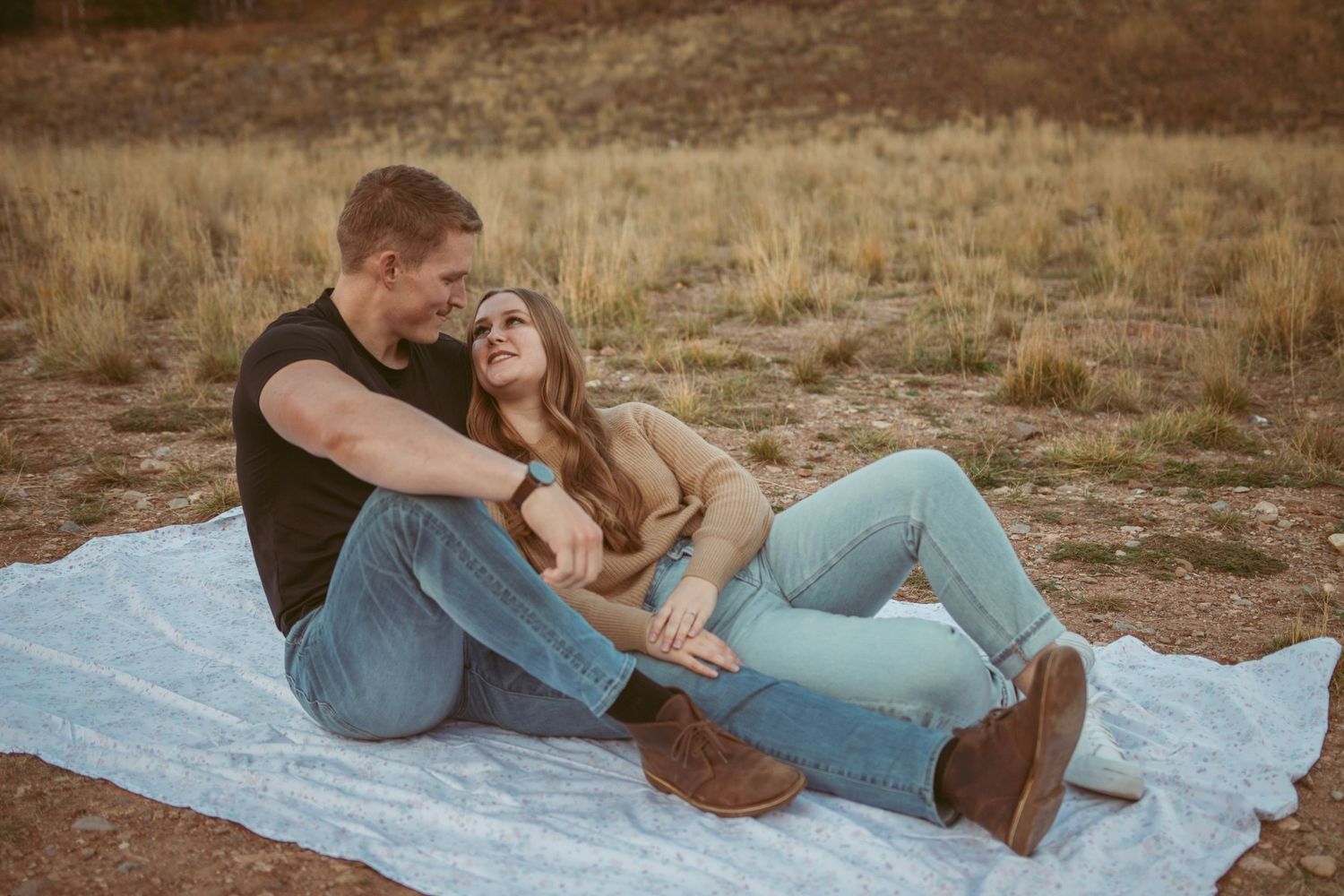 Candid moments of couple relaxing on blanket in mountain landscape.