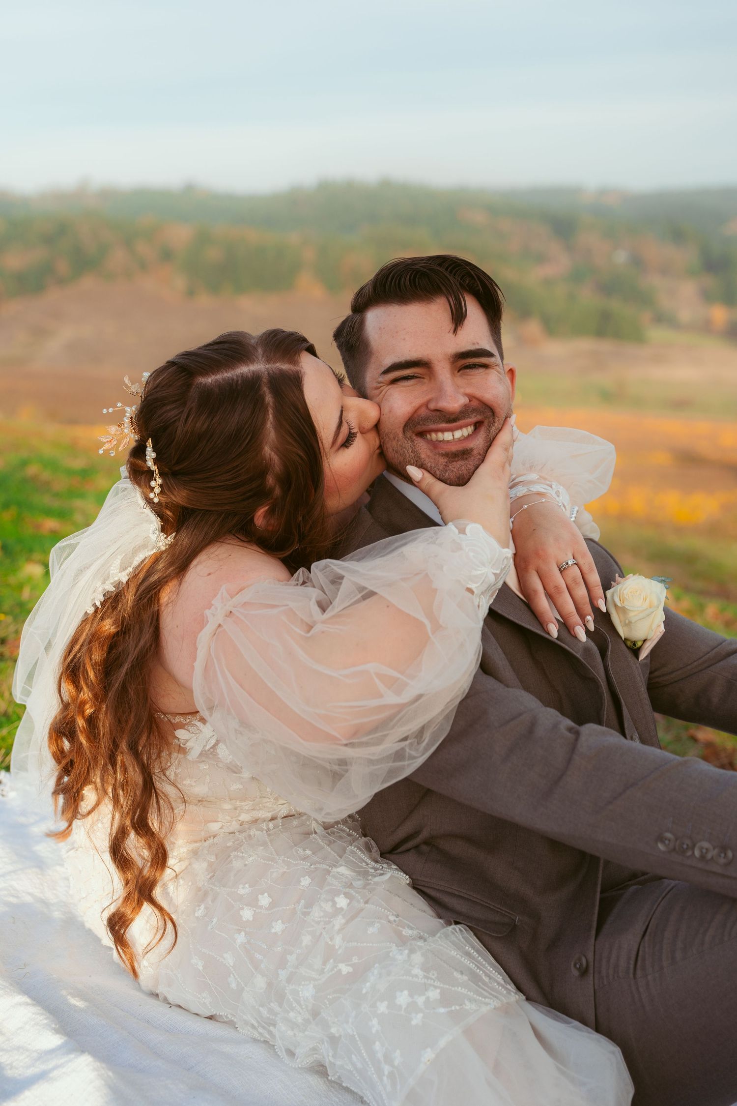 Newlyweds share a romantic moment against an autumn landscape backdrop.