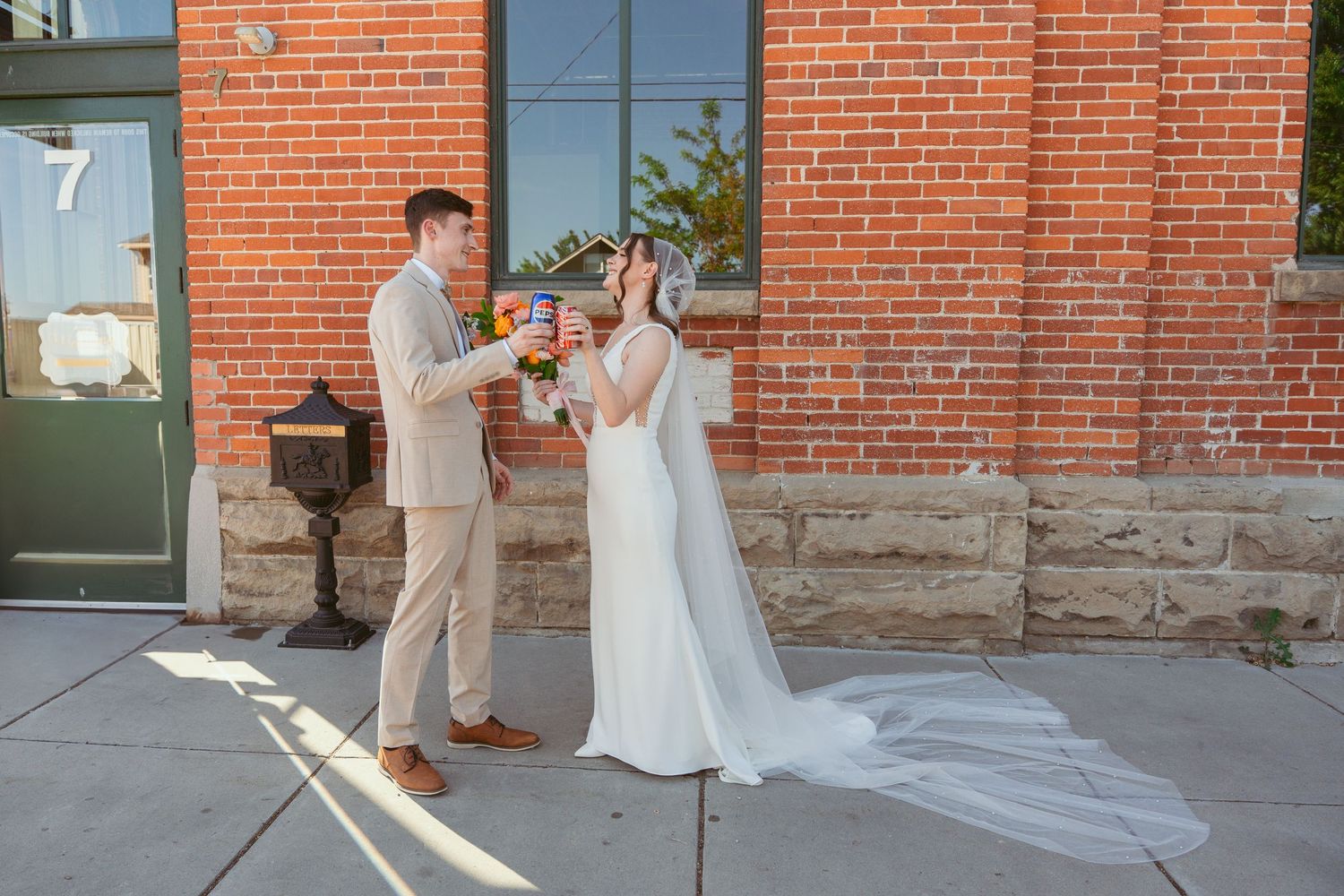 Wedding couple posing in front of a rustic brick wall with elegant attire.
