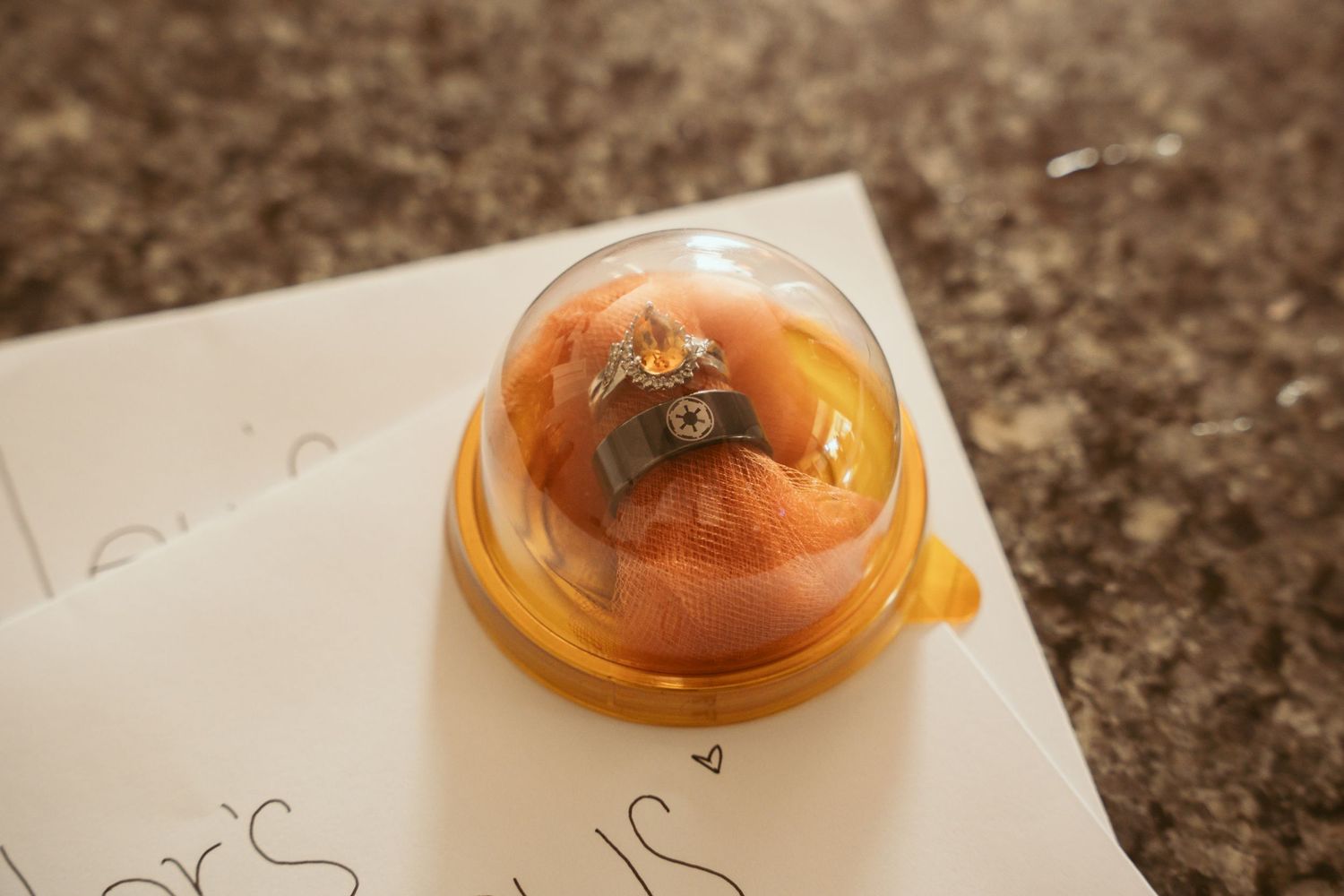 Wedding ring box displayed on handwritten paper.