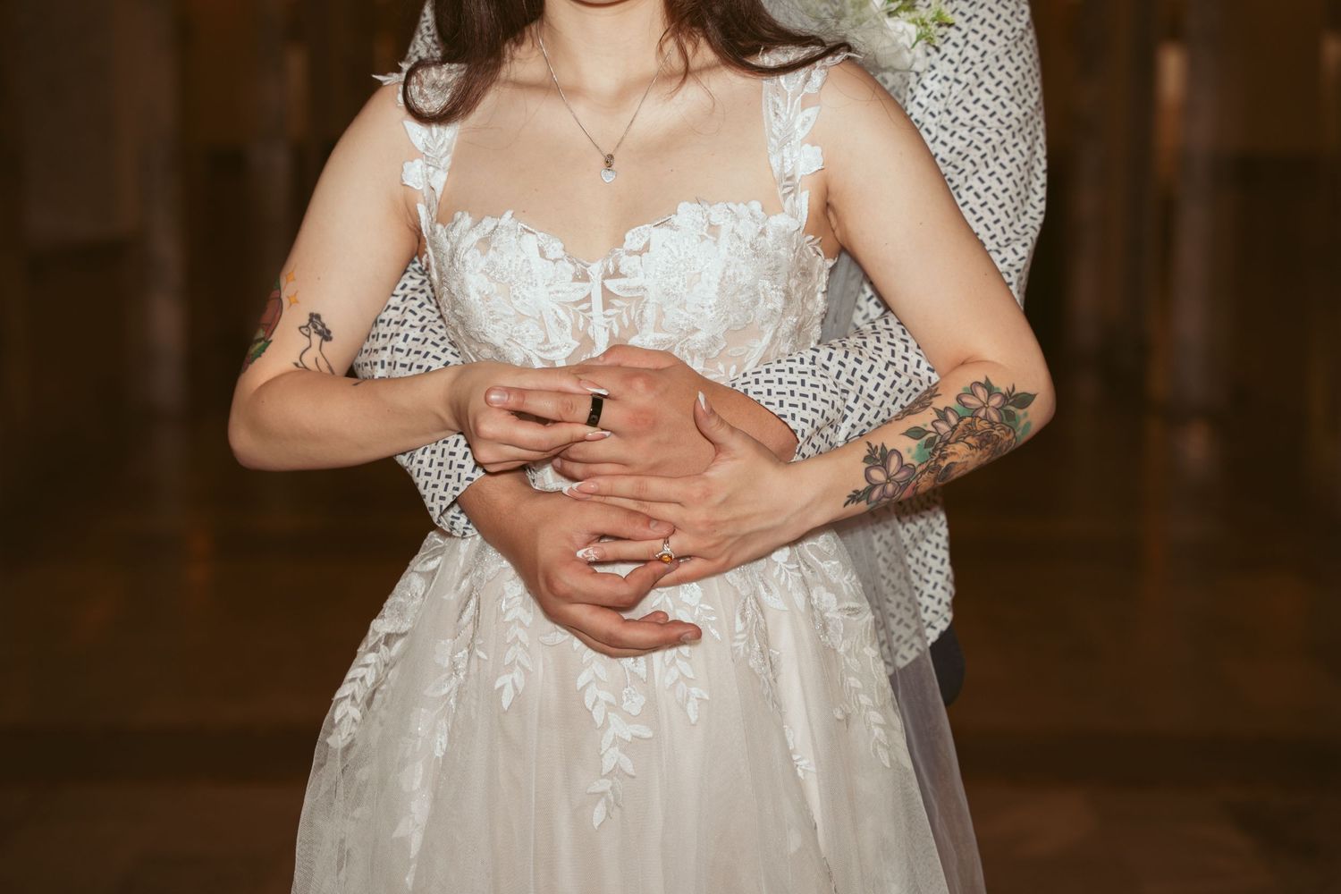 A detailed view of an elegant white lace wedding dress with delicate straps and floral details.