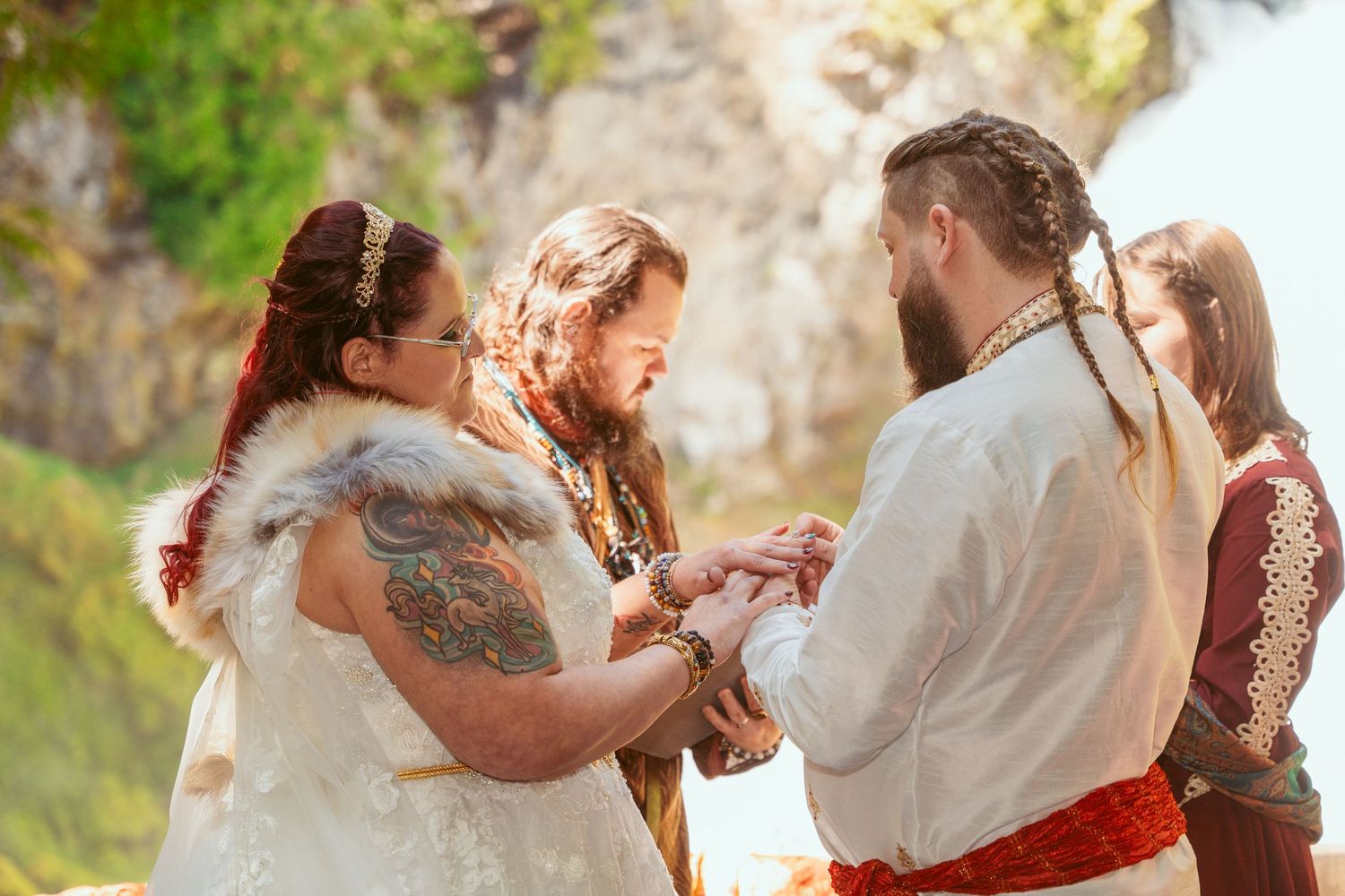Intimate forest wedding ceremony with couple in white and red attire.