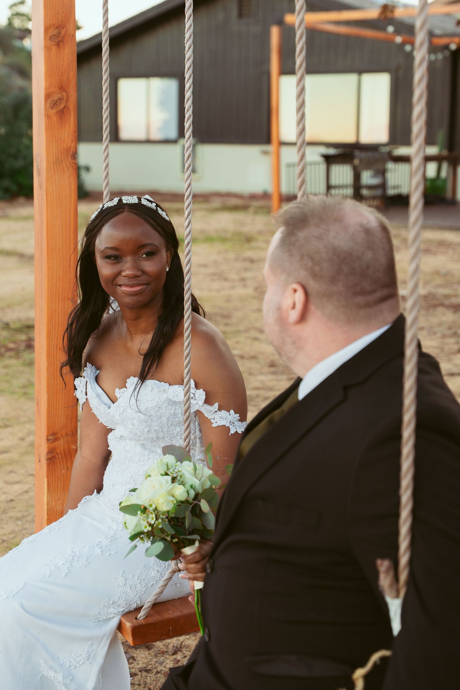 A couple sits together on rustic wooden swings during their desert wedding celebration.