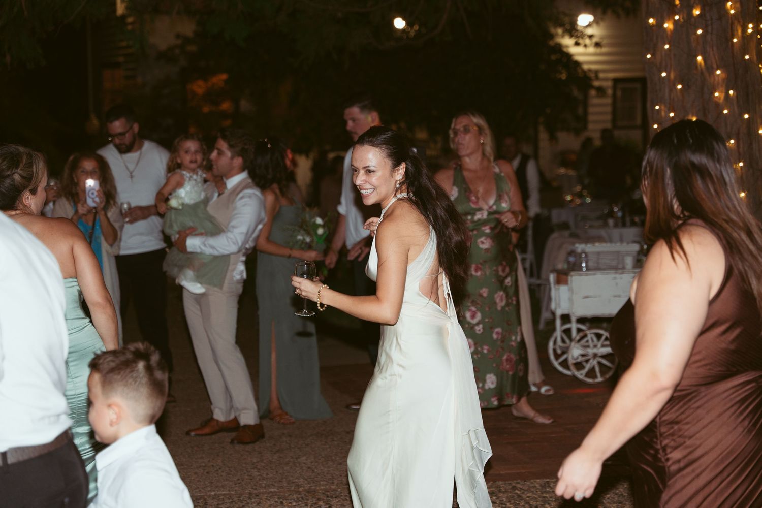 Guests dancing and celebrating at an evening wedding reception with decorative lighting.