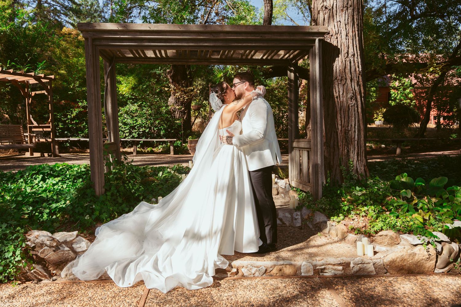 Panoramic view of wedding celebration under rustic wooden structure surrounded by trees.