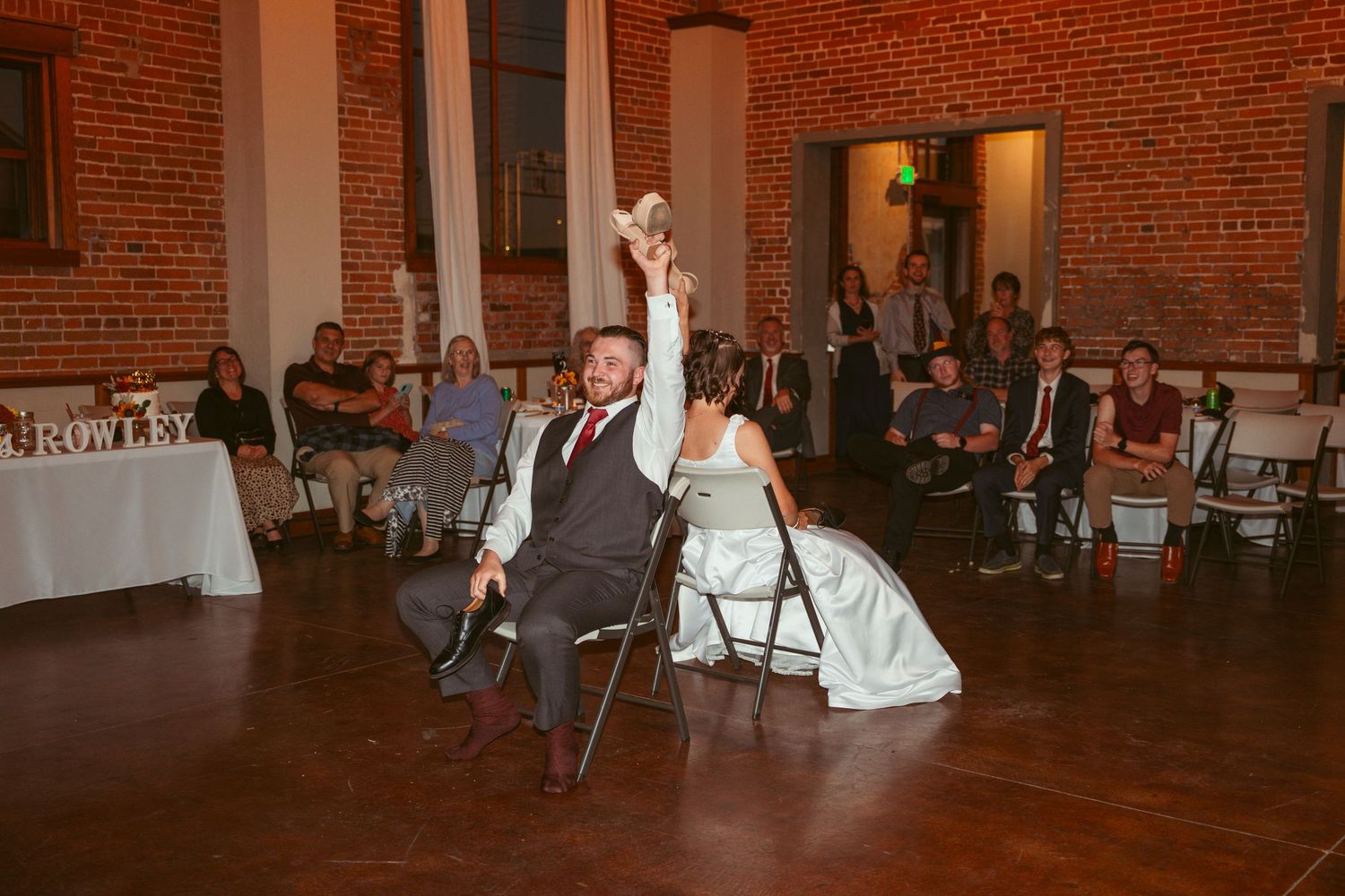 Wedding reception dancers perform coordinated moves in front of seated guests in a brick venue.