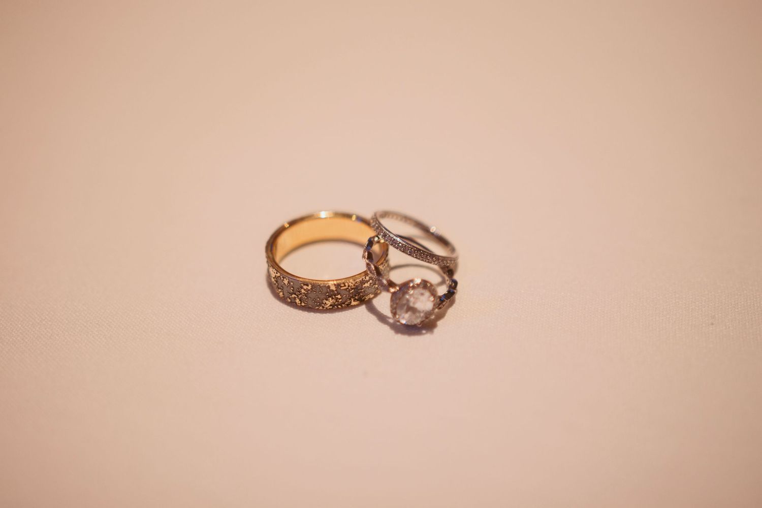 Two wedding rings photographed on beige background showing intricate details.