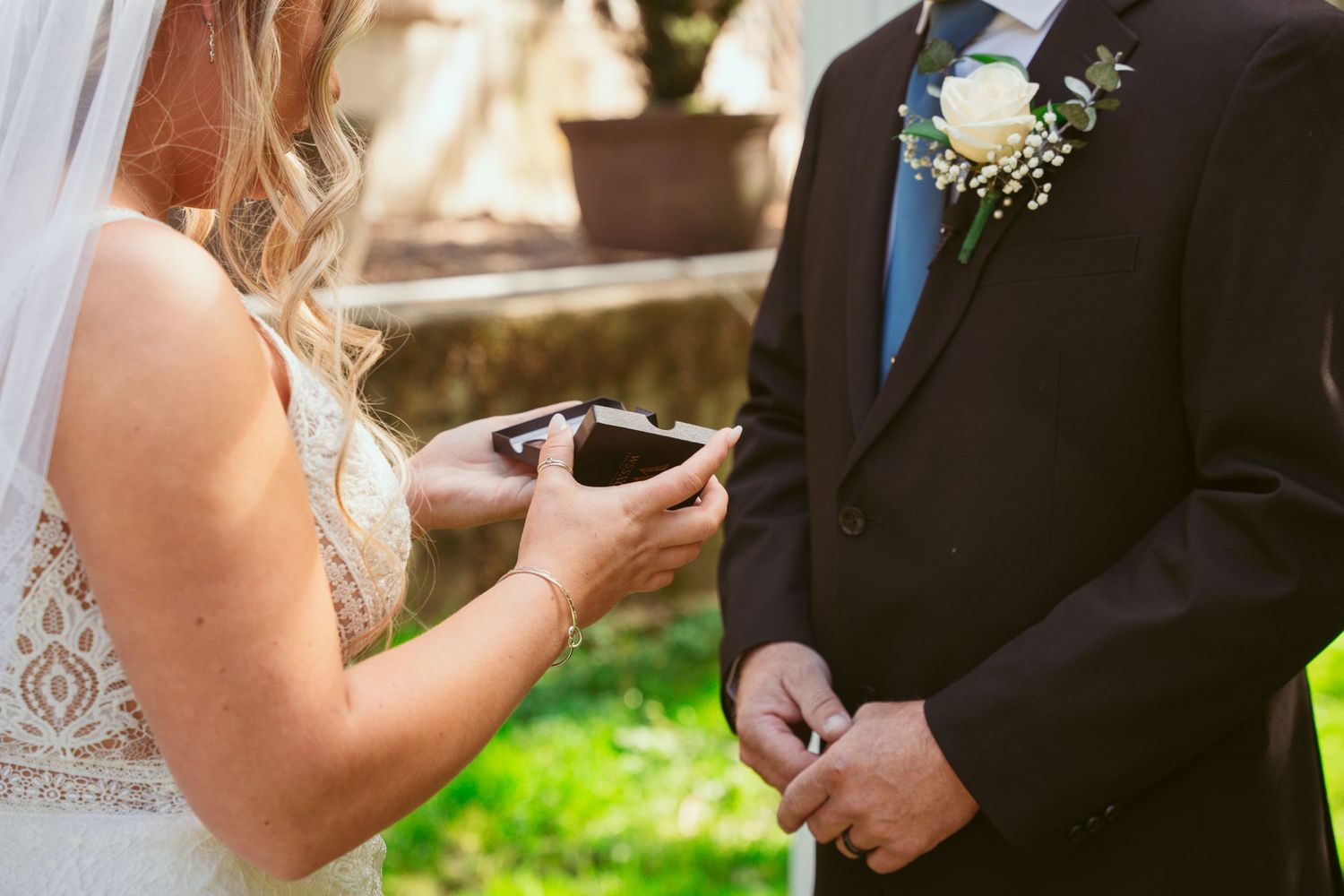 A couple shares a tender moment during their first look in a sunlit garden setting.