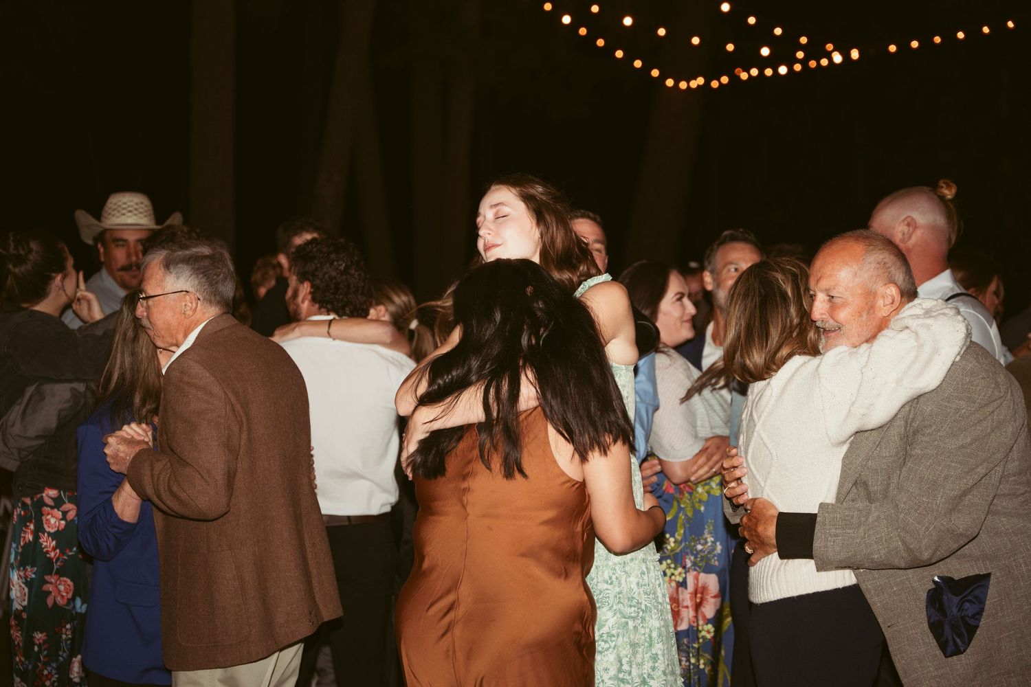 Wedding reception guests dancing and socializing at an outdoor evening celebration.