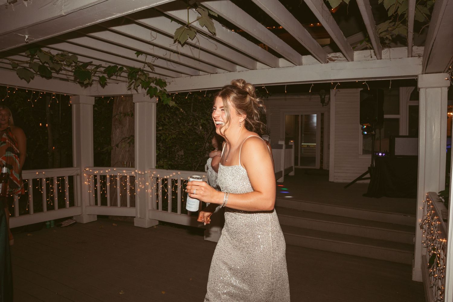 Wedding guests dancing and celebrating on an outdoor covered patio during an evening reception.