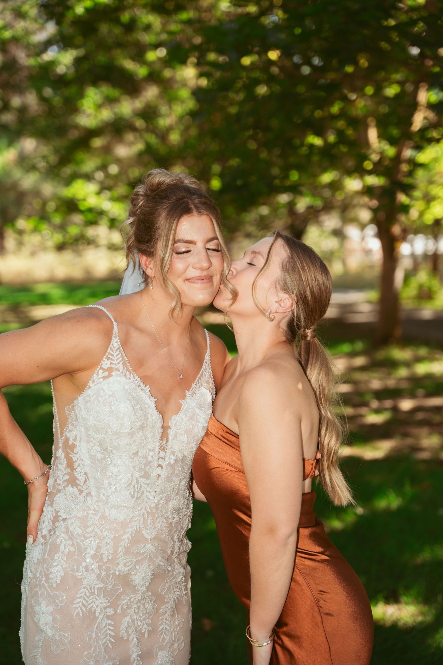 Wedding party members share joyful candid moments in a sunlit outdoor garden setting.