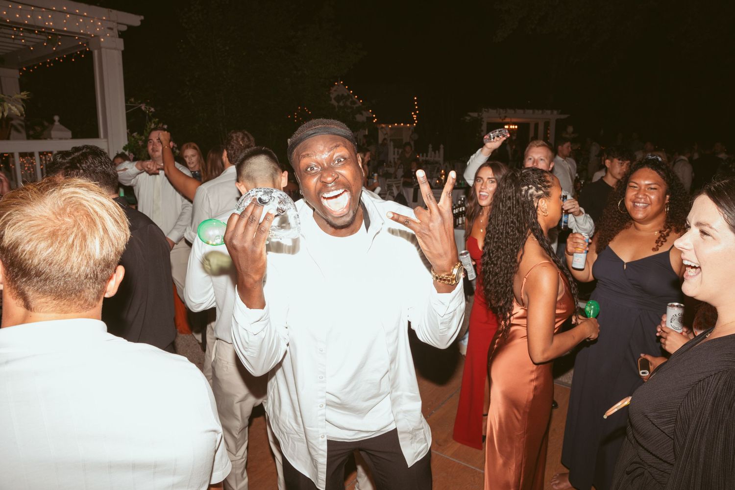 Lively crowd dancing and enjoying themselves at an evening wedding celebration.