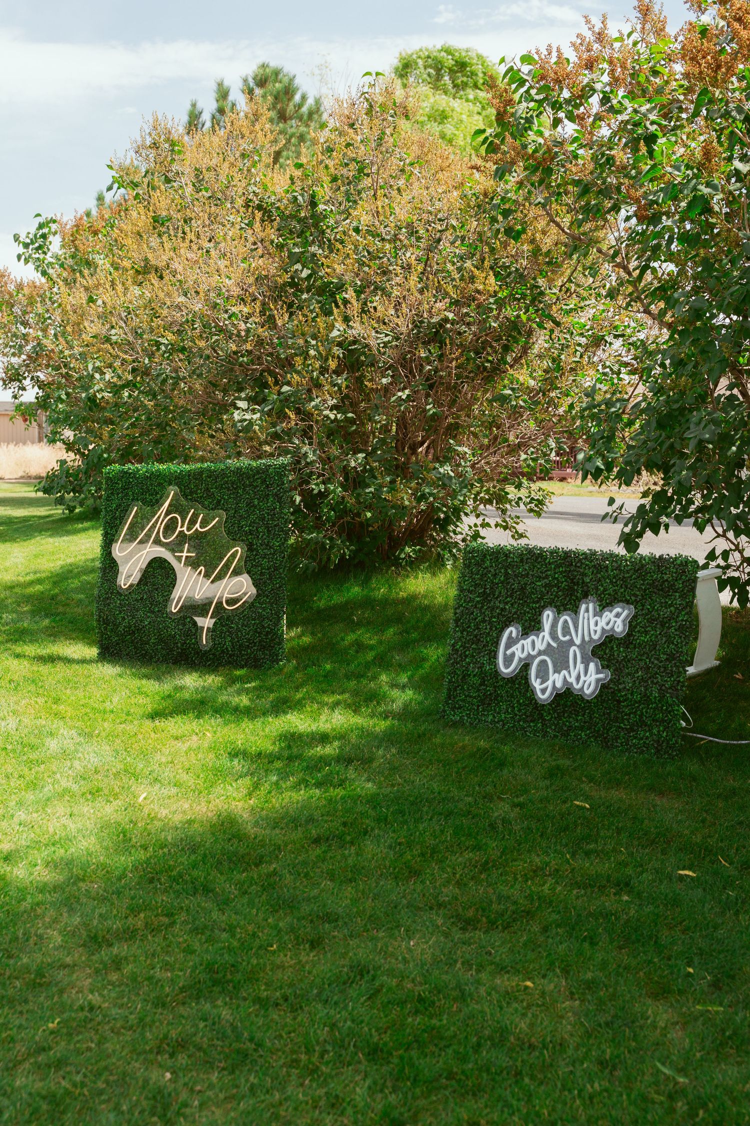 White decorative signage displayed on a lush green lawn with trees and bushes in the background.