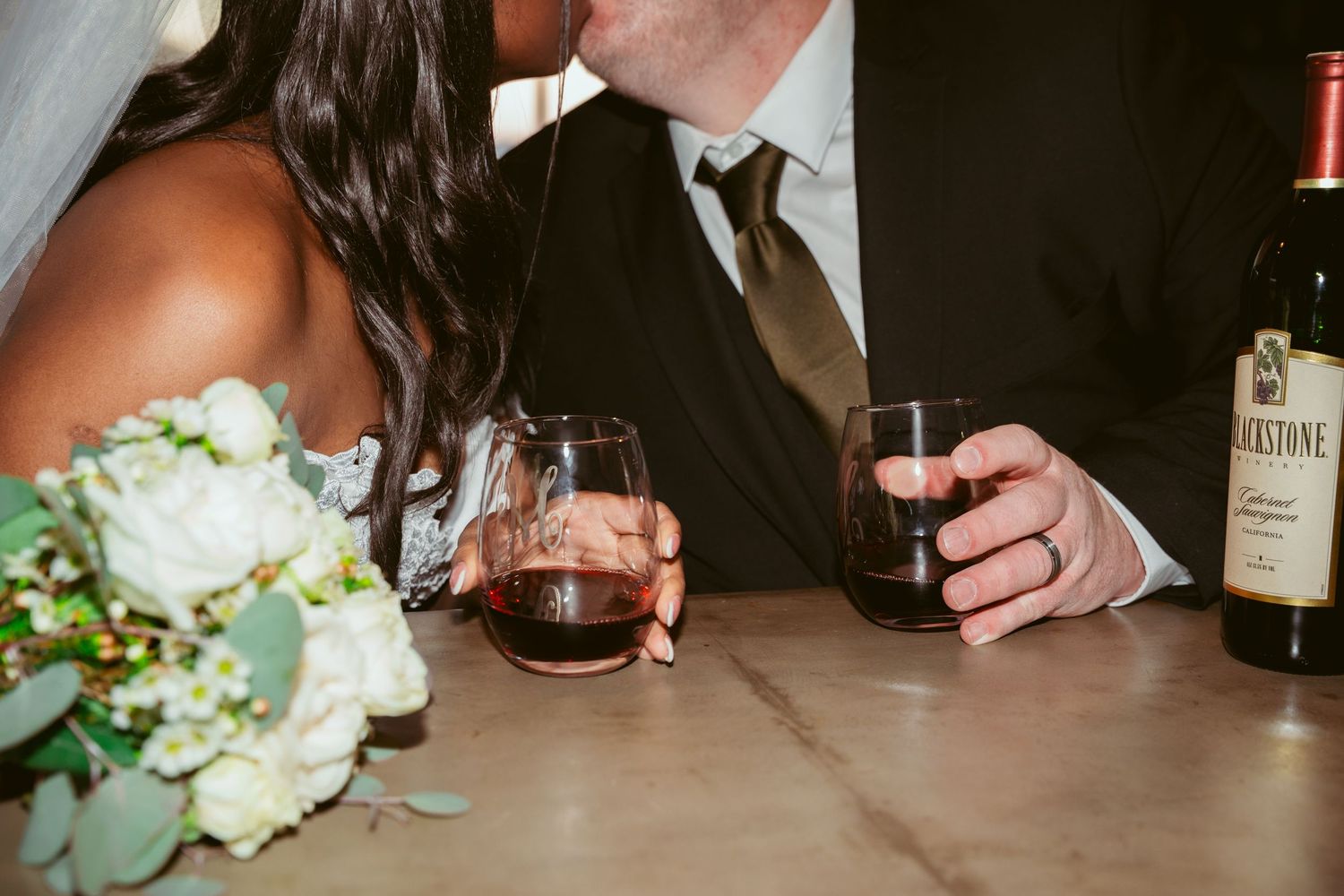 Wedding reception table with wine bottles and floral centerpieces at dusk.