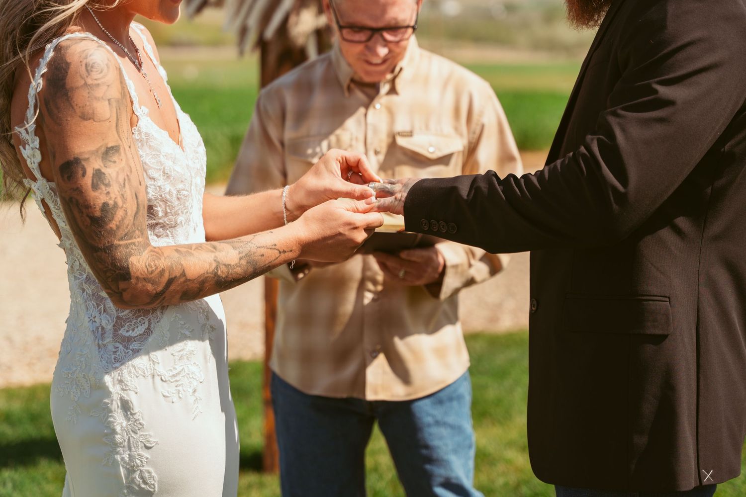 Candid wedding ceremony moment in rustic outdoor setting with mountain views.