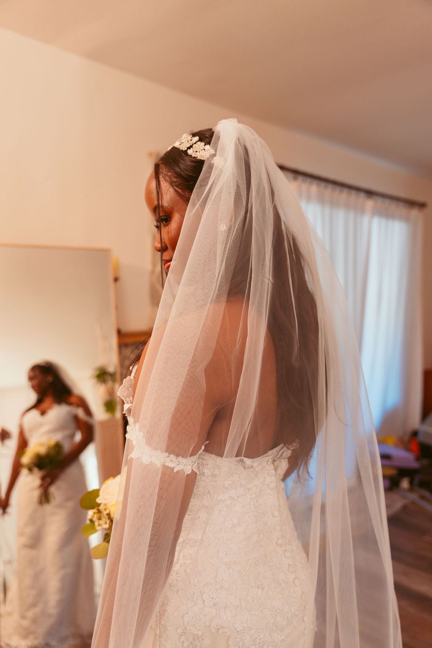 A row of white wedding dresses hanging in a bridal preparation room with soft lighting.