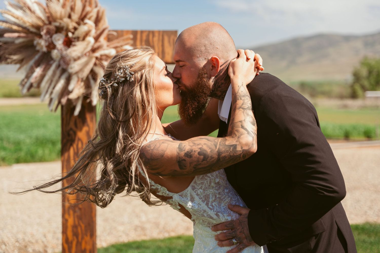 Romantic wedding couple posing in a scenic outdoor setting with mountains in background.