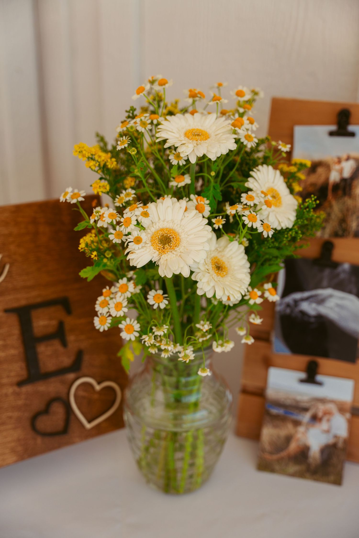 White gerbera daisies and wildflowers arranged in a mason jar centerpiece.