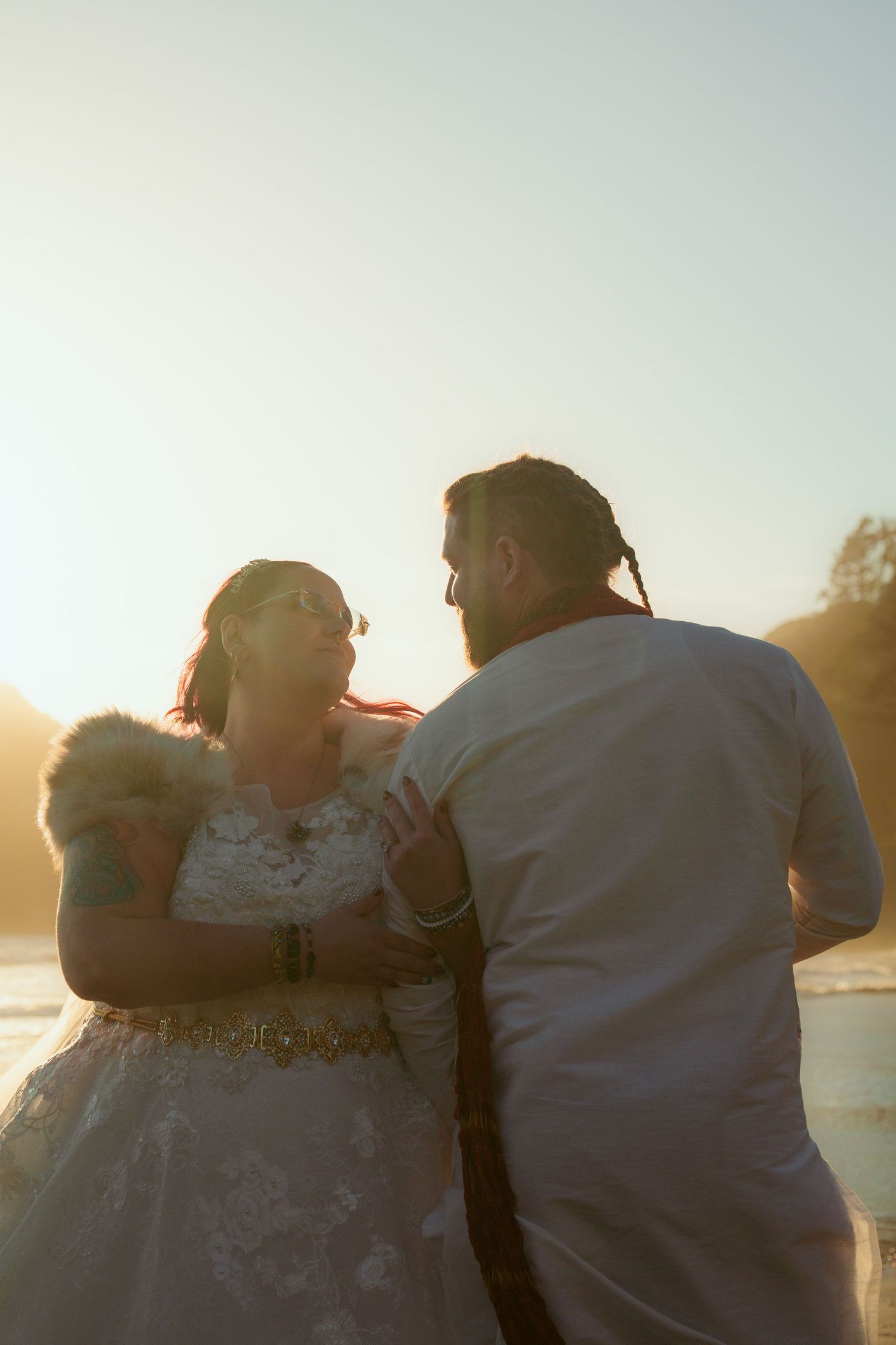 Intimate sunset beach wedding portrait with golden light and coastal scenery.