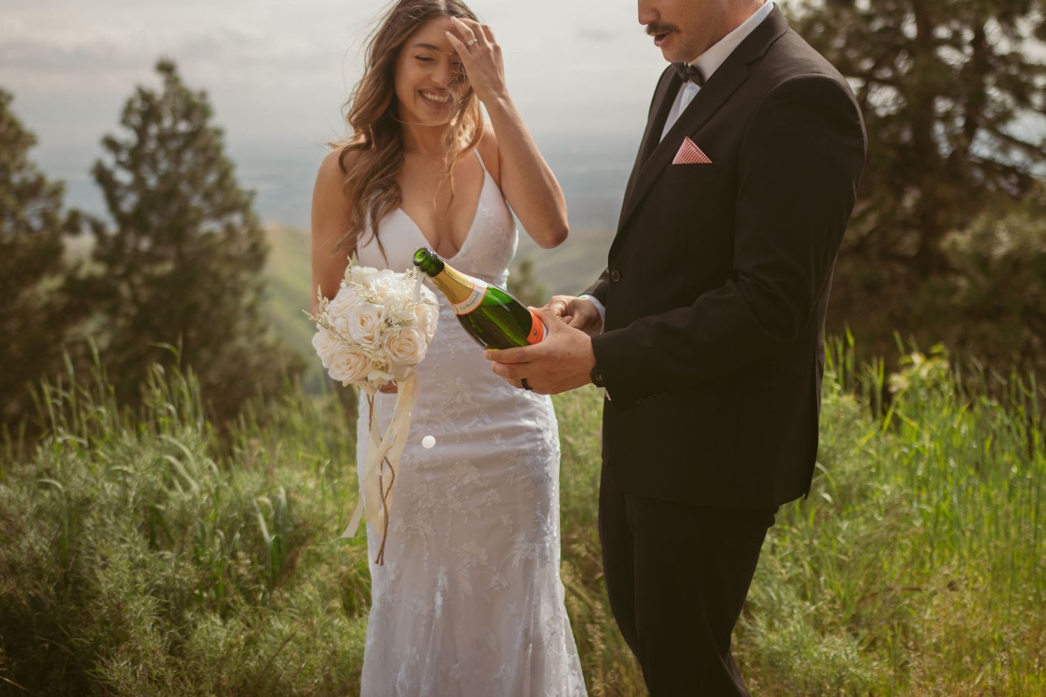 A couple shares a celebratory toast during their outdoor mountain wedding.