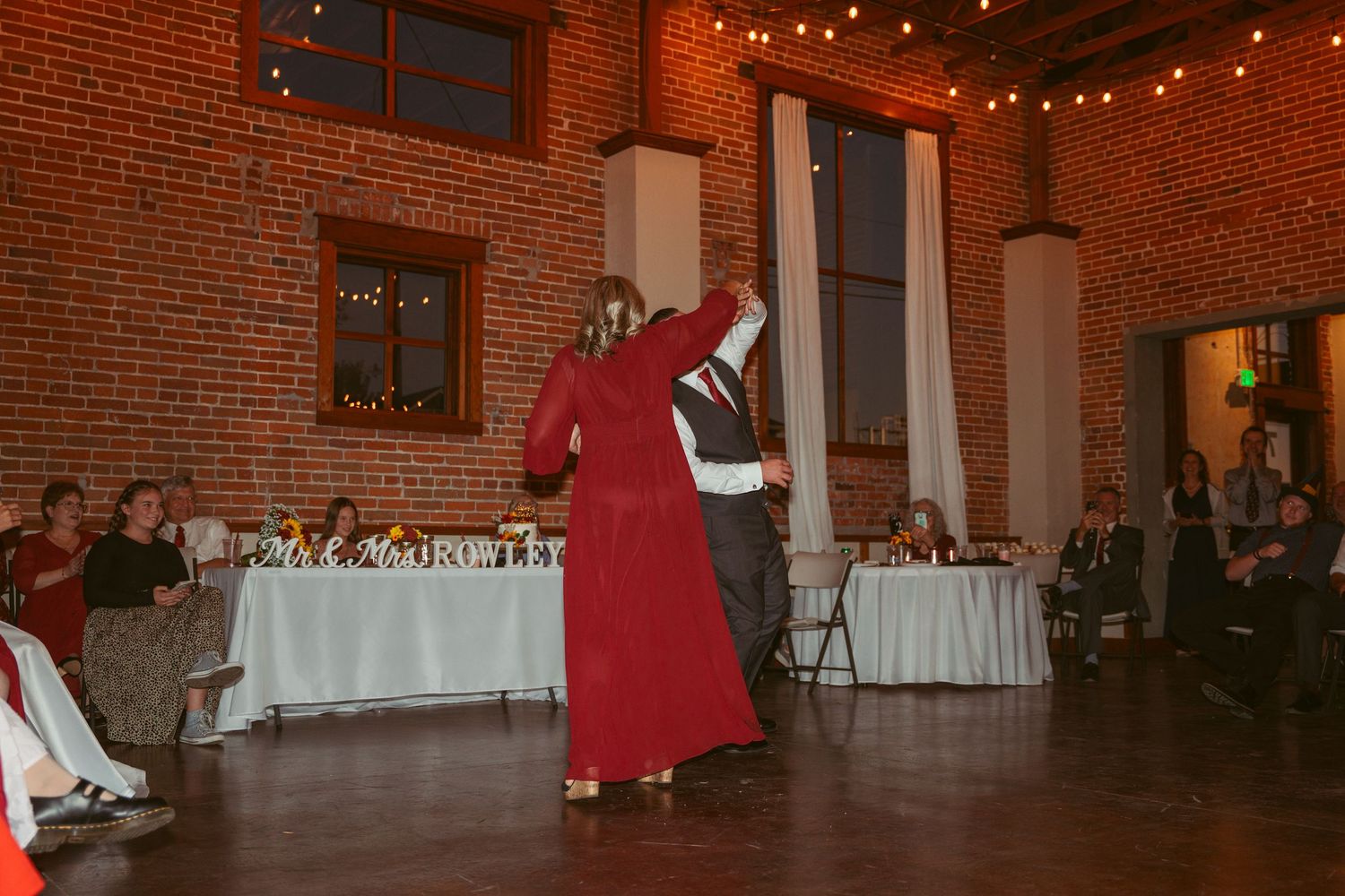 Event space with exposed brick walls and string lights during evening celebration.