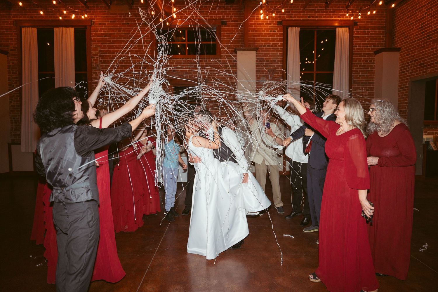 Wedding guests create a streamer tunnel effect during reception celebration.