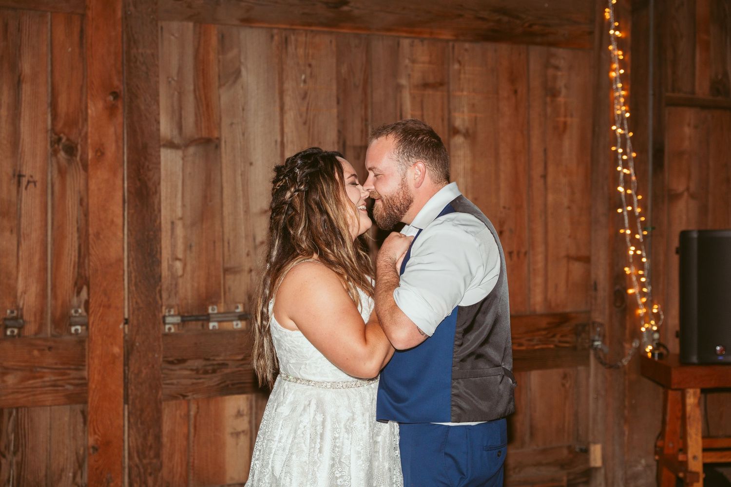 A romantic dance moment captured in a barn with wooden walls and warm lighting.