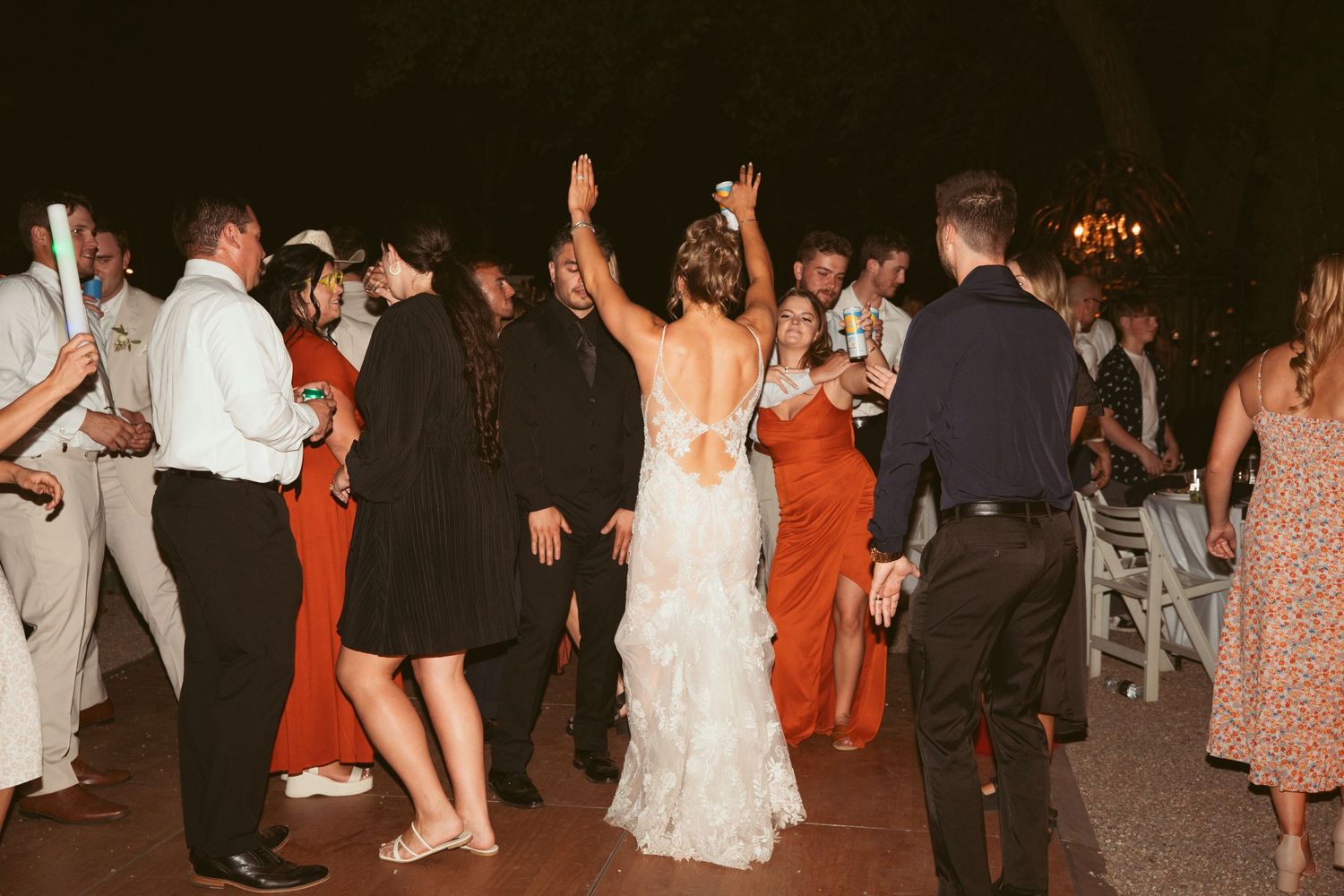 Wedding celebration on outdoor dance floor with guests dancing in evening light.