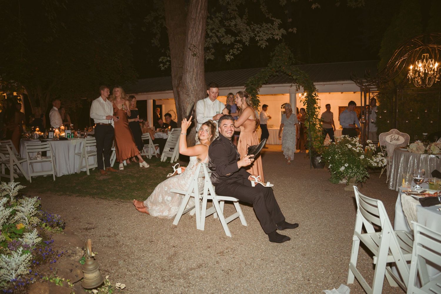 Evening wedding reception venue with white chairs arranged outdoors.