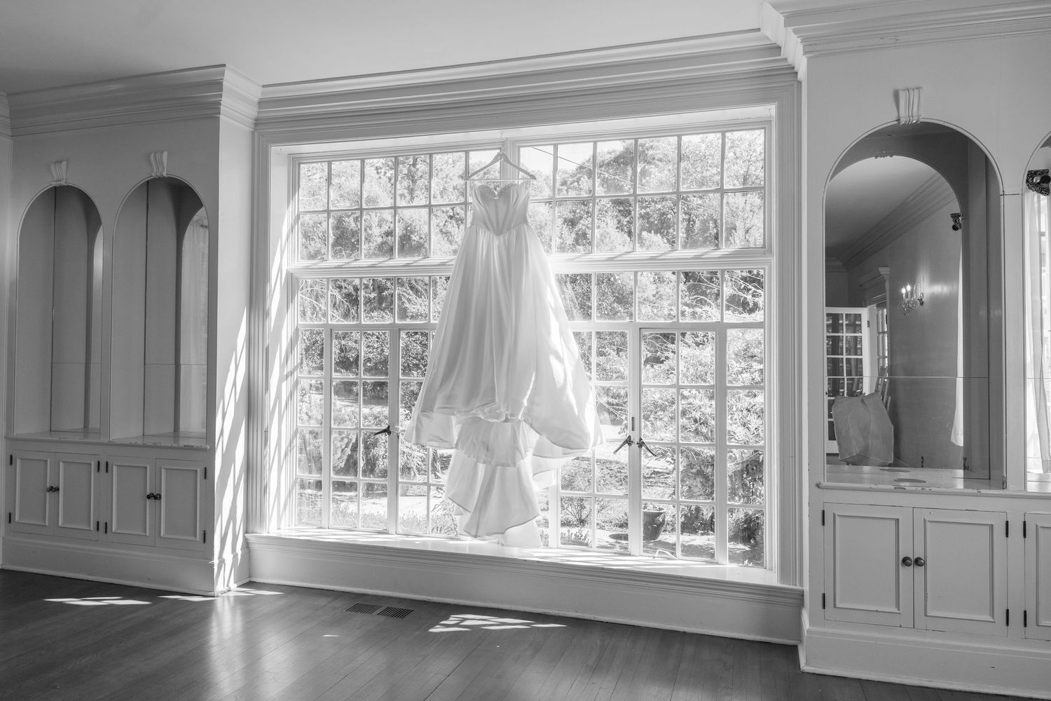 Elegant white kitchen interior with large windows, custom cabinetry, and natural lighting.