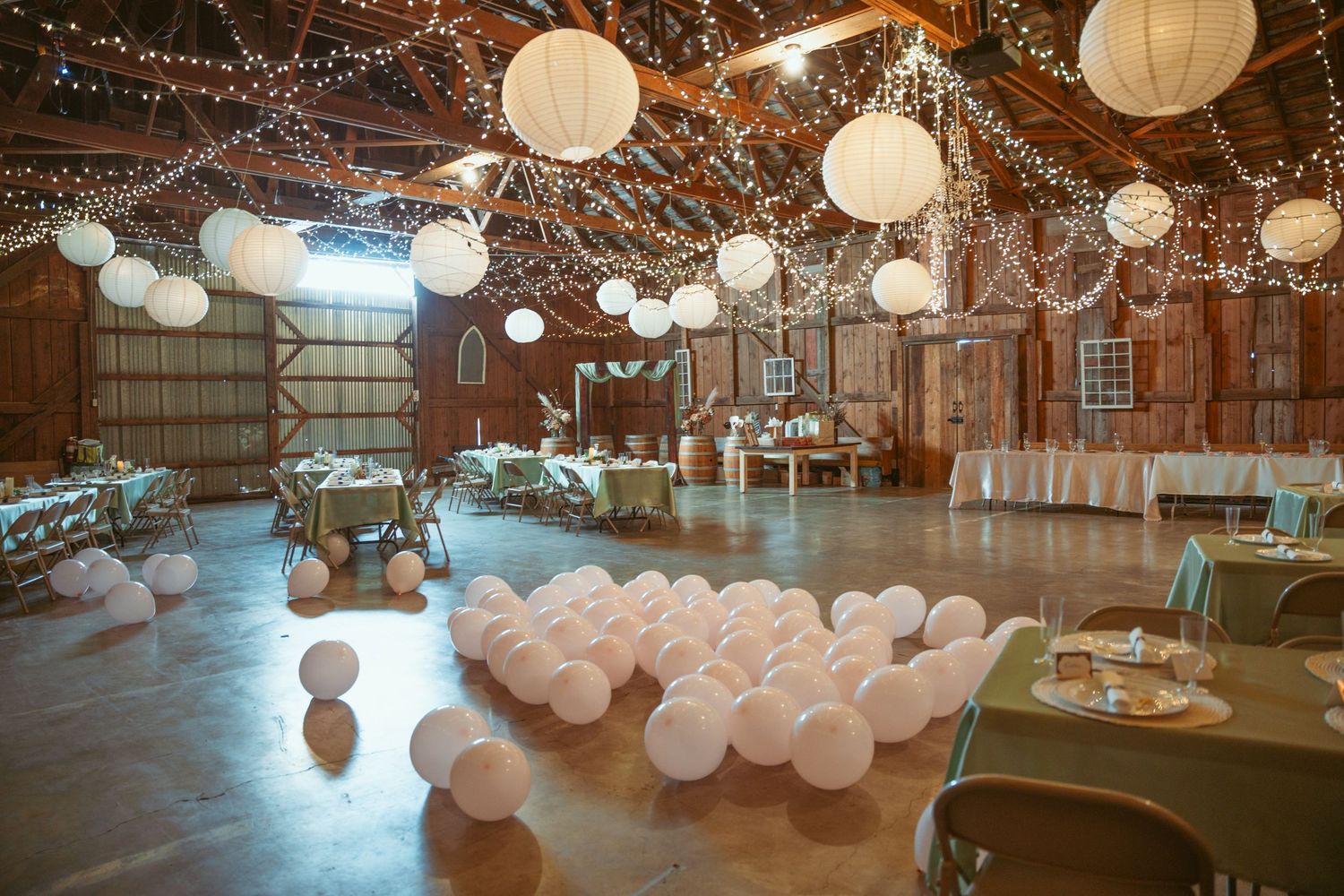 Wedding reception space with hanging paper lanterns and twinkle lights creating magical atmosphere.