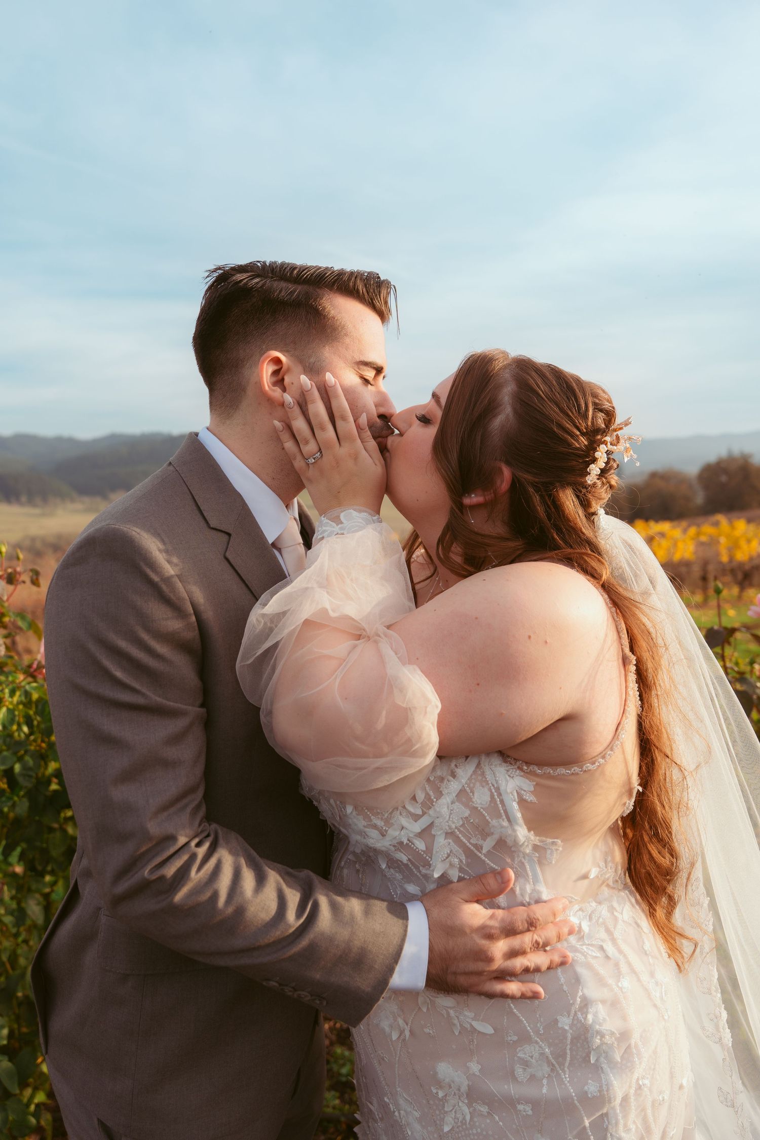 Romantic wedding portrait in vineyard with autumn colors and mountains in background.