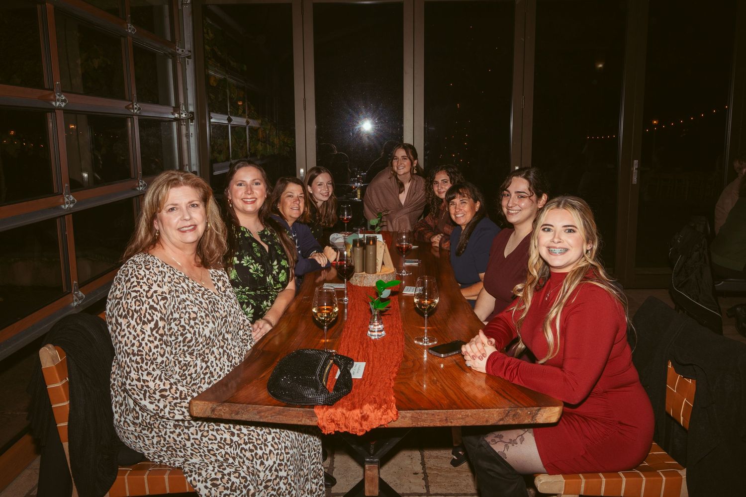 Group of people seated at round tables in a dimly lit restaurant setting.
