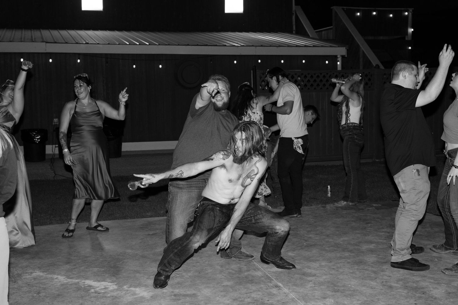 Black and white photo of people dancing at an evening celebration.