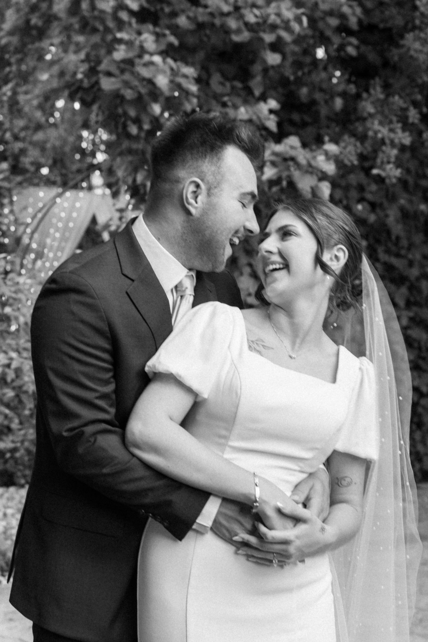 Black and white wedding portraits capturing intimate moments between newlyweds in a garden setting.