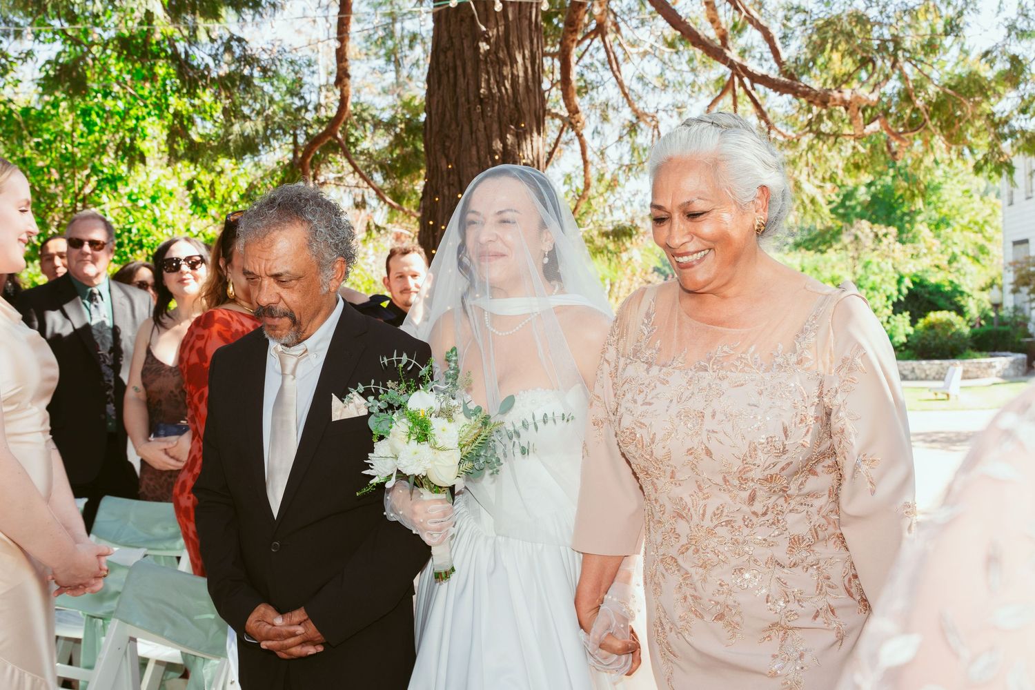 Wedding guests celebrating during an outdoor garden ceremony with natural greenery.