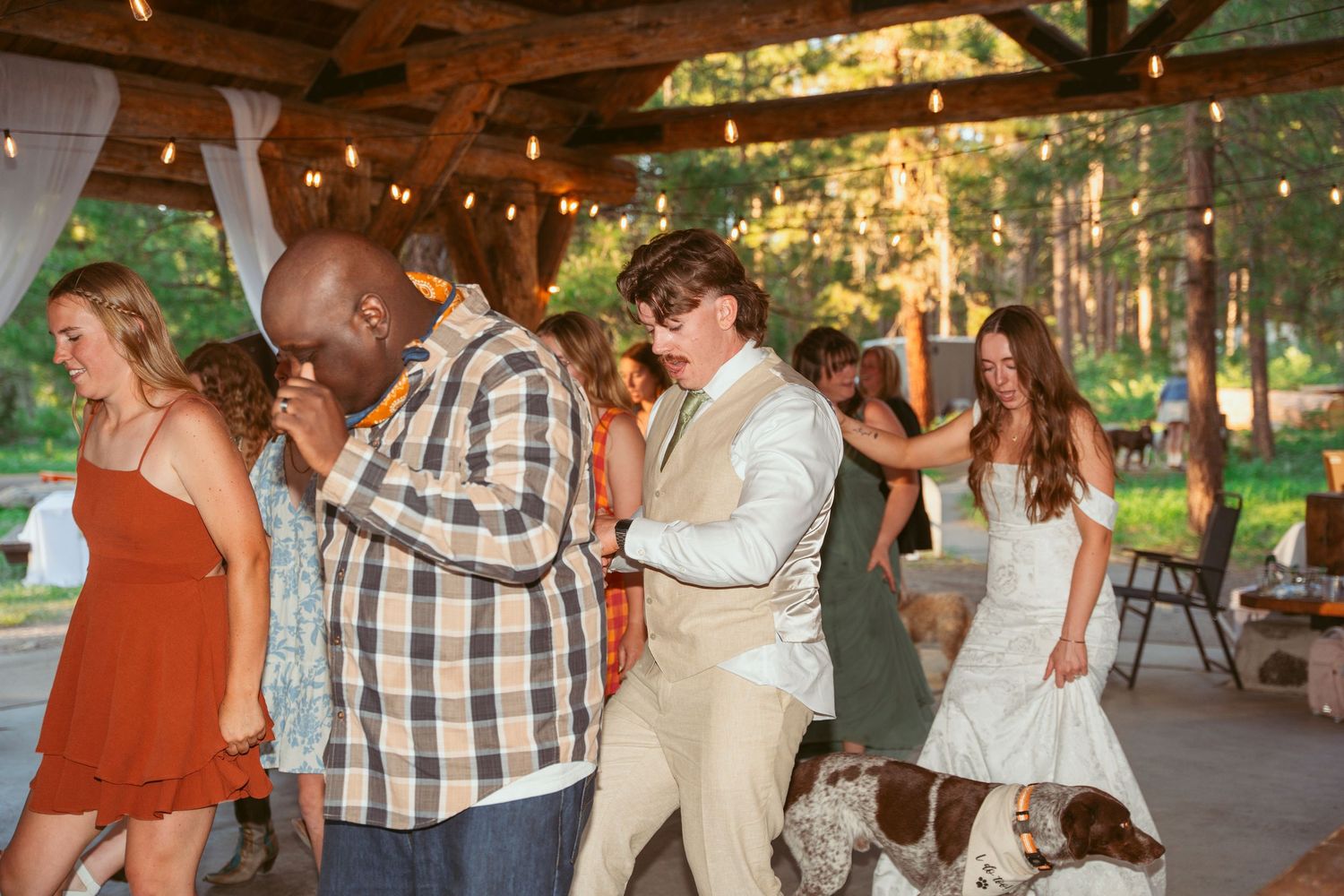 Guests enjoying a lively dance celebration under a rustic wooden pavilion.
