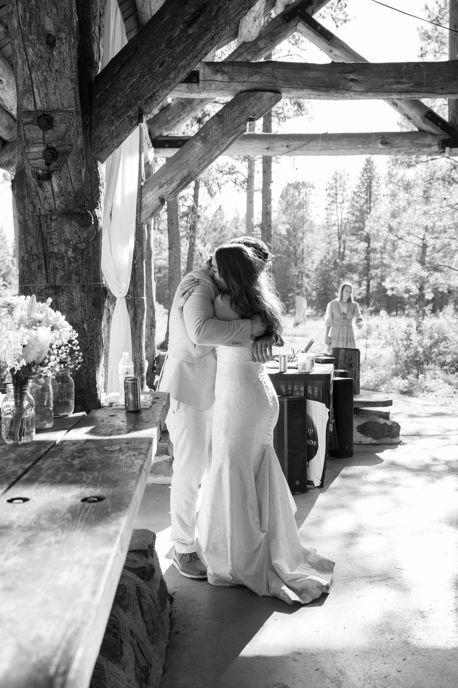 Black and white photo of wedding dance in rustic outdoor pavilion.