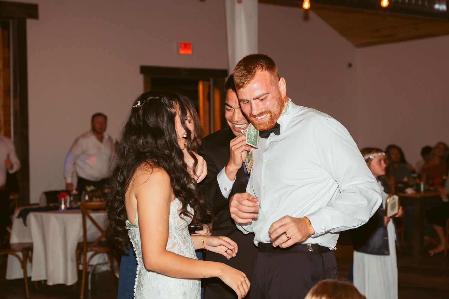 Guests dancing and mingling at an indoor wedding reception with ambient lighting.