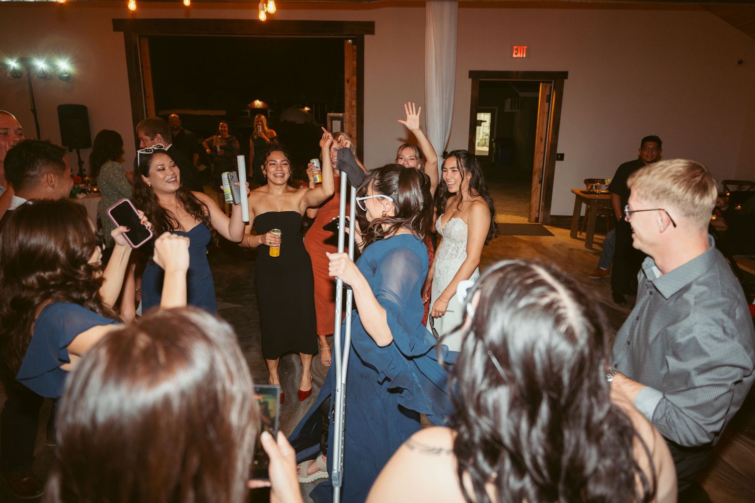 Celebration attendees wave glow sticks while dancing at an indoor venue.