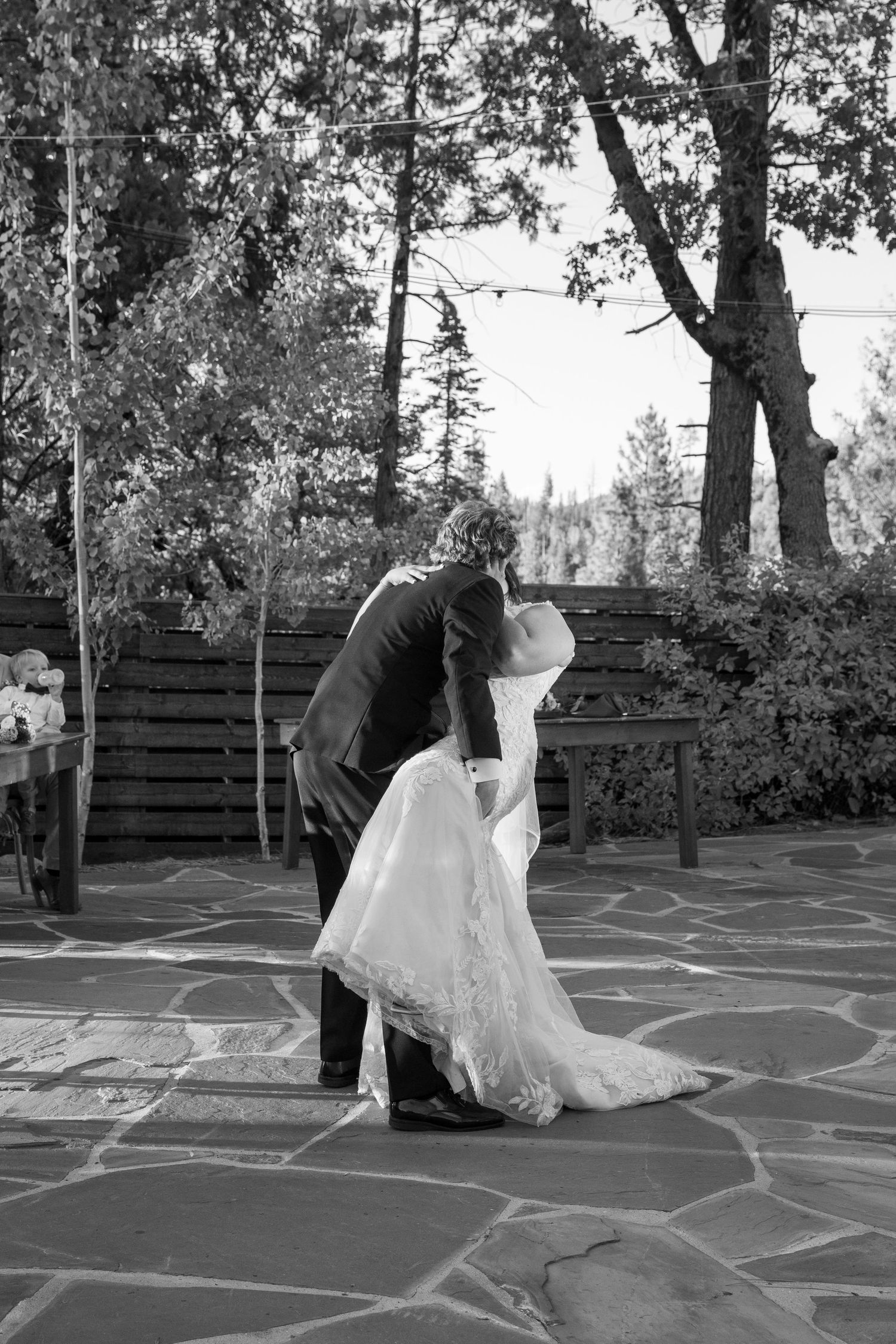 Black and white capture of wedding dance sequence on outdoor stone patio at sunset.