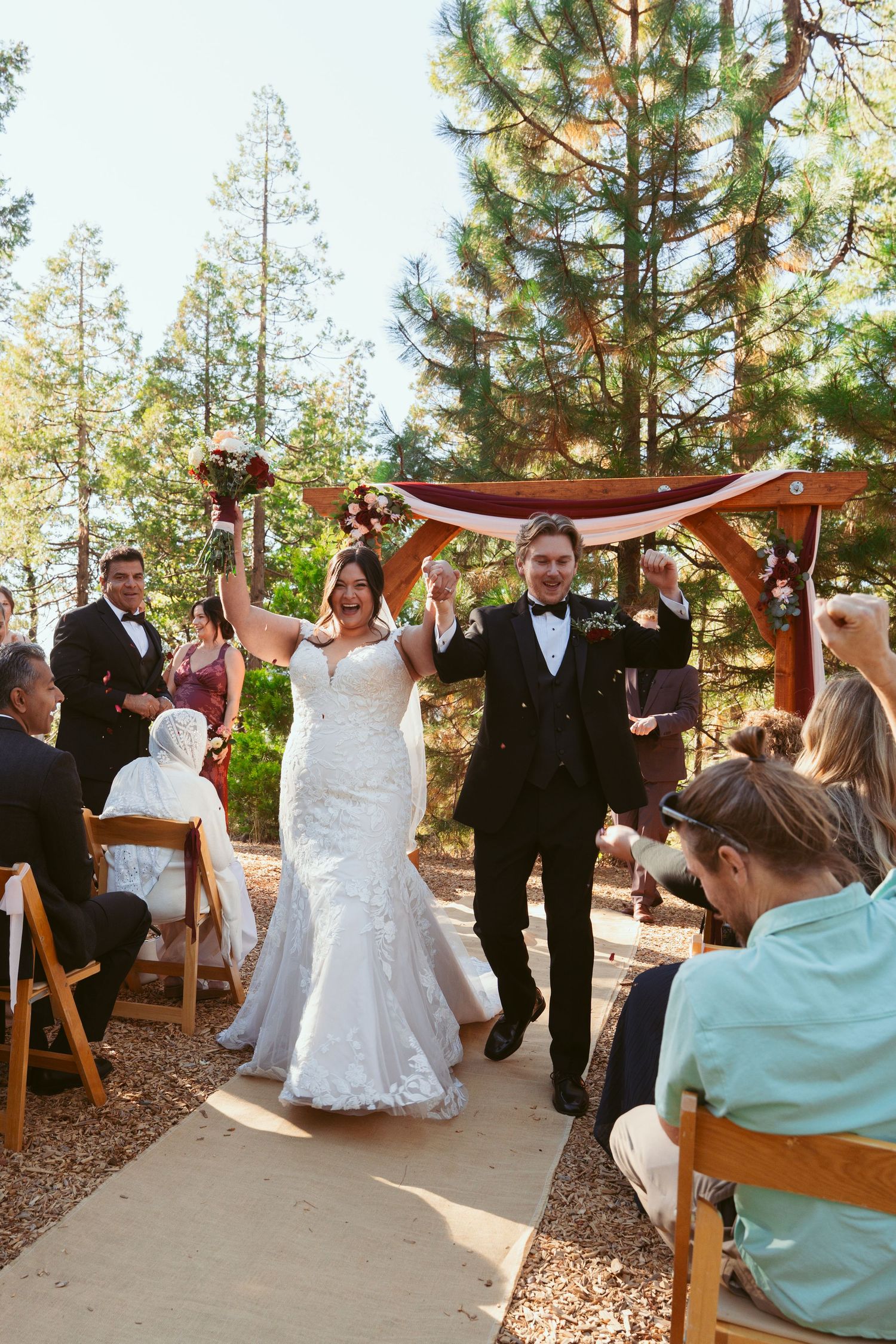 Wedding celebration in a pine forest with guests watching the couple's first moments as newlyweds.